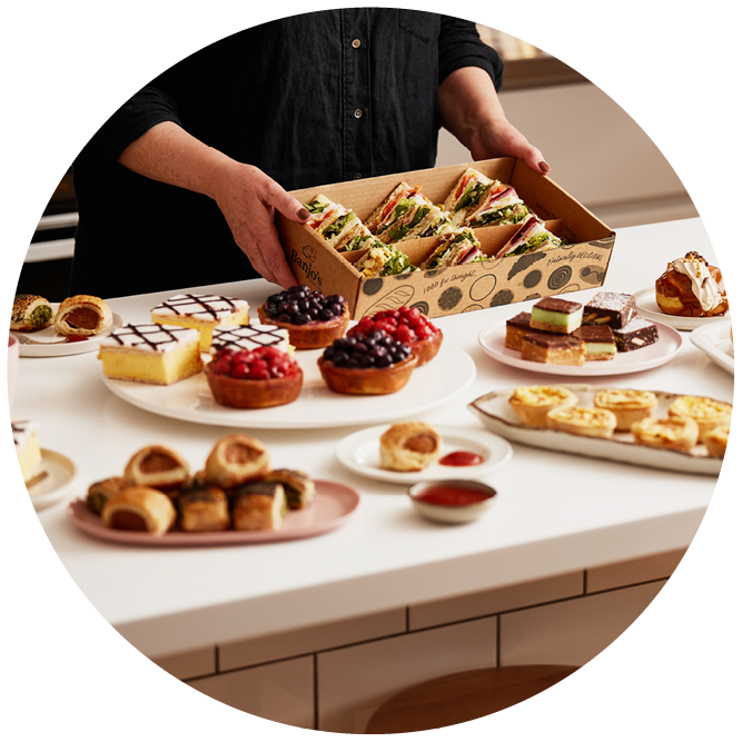 a person placing a Banjo's Sandwich Platter down on a bench filled with more Banjo's Platter products